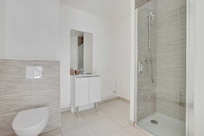 Ein modernes Badezimmer mit Toilette, Waschbecken mit Spiegel und einer Duschkabine.