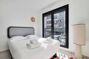 Ein Hotelzimmer mit Bett, einem Fenster mit Blick auf die Stadt und einer Lampe.
