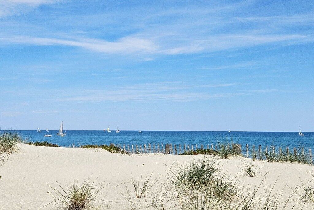 A beach with sand dunes and a clear blue sky.