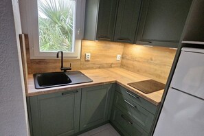 A kitchen with a window, a sink, and a refrigerator. - Holiday apartment with 1 bedroom (Leucate)