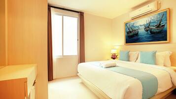 A hotel room with a bed, a painting, a window with curtains, and an air conditioning unit.