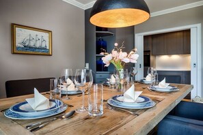 A dining table set with plates, glasses, and cutlery, a vase with flowers, and a framed picture on the wall. - Holiday home in Sylt with 2 bedrooms (Westerland)