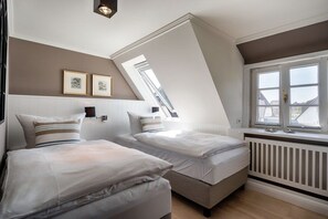 A bedroom with two beds, a sloped ceiling, a window, and a radiator. - Holiday home in Sylt with 2 bedrooms (Westerland)