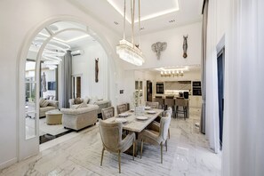 A spacious living room with a dining area, a kitchen, and a view through an archway. - 3br Luxurious Villa Gold Chariott (Bangtao)