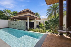 A swimming pool with a wooden deck, a covered patio, and tropical plants. - 3br Luxurious Villa Gold Chariott (Bangtao)