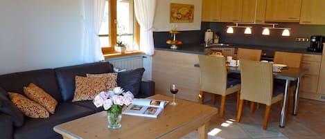 A living room with a sofa, coffee table, and a dining area with chairs and a table.
