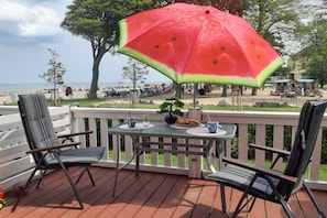 A deck with two chairs and a table, a large watermelon umbrella, and a view of the beach. - Holiday apartment Haus Meeresblick 319637 (Kühlungsborn - West)