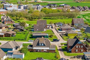 Zona residencial com casas, uma avenida principal e campos verdes.