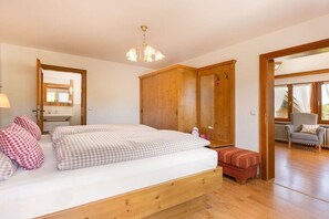 A bedroom with a wooden bed, a nightstand, a mirror, and a wardrobe. - Landhaus Pichler holiday apartment Kienberg (Ruhpolding)