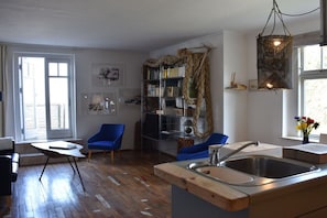 A modern kitchen with a wooden countertop, a built-in sink, and a bookshelf with decorative rope. - Holiday apartment with 1 bedroom (Lubmin)