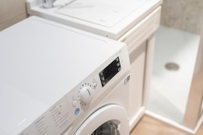 A front view of a white washing machine with a digital display and control panel. - Ortigia Inner Suites (Siracusa)