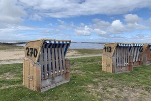 Two beach huts with numbers 270 and 113, made of wicker and wood, on a grassy area with a view of the sea. - Wadden Sea walkers - calm winds (Wurster Nordseeküste)