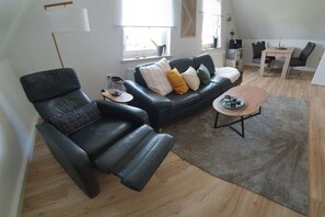 A modern living room with a black leather sofa, a wooden coffee table, and a grey rug. - Holiday apartment with 2 bedrooms (Weißenstadt!)