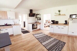 A modern kitchen with white cabinetry, a microwave, and a coffee machine. - Holiday apartment with 2 bedrooms (Weißenstadt!)