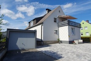 A modern two-story house with a garage, a balcony, and a small garden area. - Holiday apartment with 2 bedrooms (Weißenstadt!)