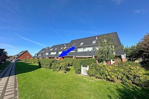A residential building with a sloped roof, a paved driveway, and well-maintained lawns. - Holiday apartment with 1 bedroom (Westerland)