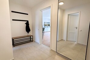 A hallway with a bench, a coat rack, and a door leading to a balcony. - Holiday apartment with 1 bedroom (Westerland)