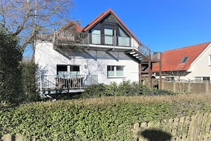 Ein zweistöckiges Haus mit Balkon, rotem Dach und weißer Fassade.