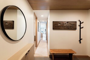 A hallway with a wooden bench, a mirror, and a wall-mounted sign with a quote. - Ski-In/Out Condo, Hot Tub & Rooftop Fire Pit (Park City)