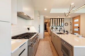 A modern kitchen with a central island, built-in oven, and a stainless steel range. - Ski-In/Out Condo, Hot Tub & Rooftop Fire Pit (Park City)