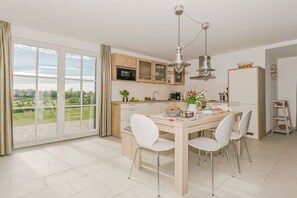 A modern kitchen with a dining area, large windows, and a view of greenery. - Black-headed gull with a view of the Baltic Sea (Zierow)