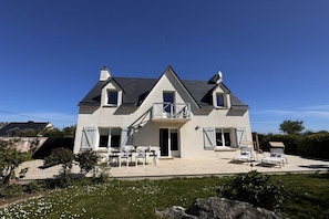 A two-story house with a balcony, a patio with outdoor furniture, and a well-maintained lawn. - Villa "Mechou Men Bras" (Brignogan Plages)