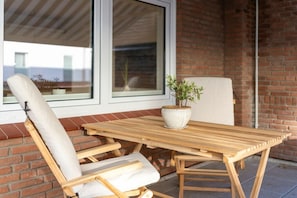 Un conjunto de mesa y sillas de madera frente a una pared de ladrillo con una ventana.