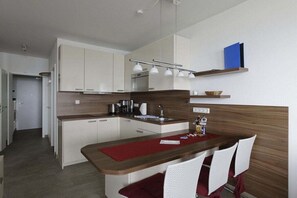 A compact kitchen with a central island, white cabinetry, and a red placemat. - Döser Seedeich 7, Apt. 17 (Cuxhaven)