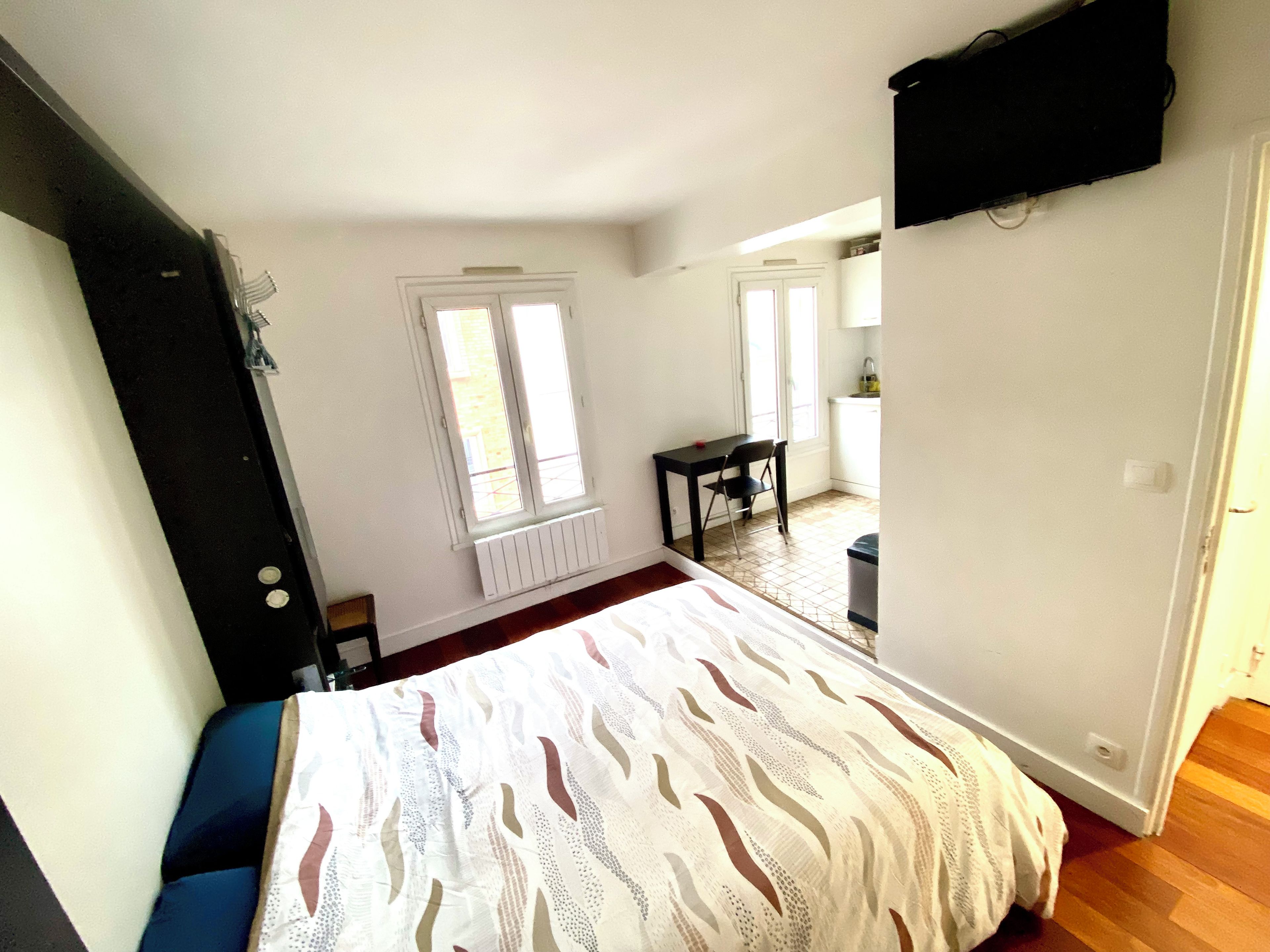 Une chambre à coucher avec un lit, une fenêtre, un radiateur, un bureau et une chaise.