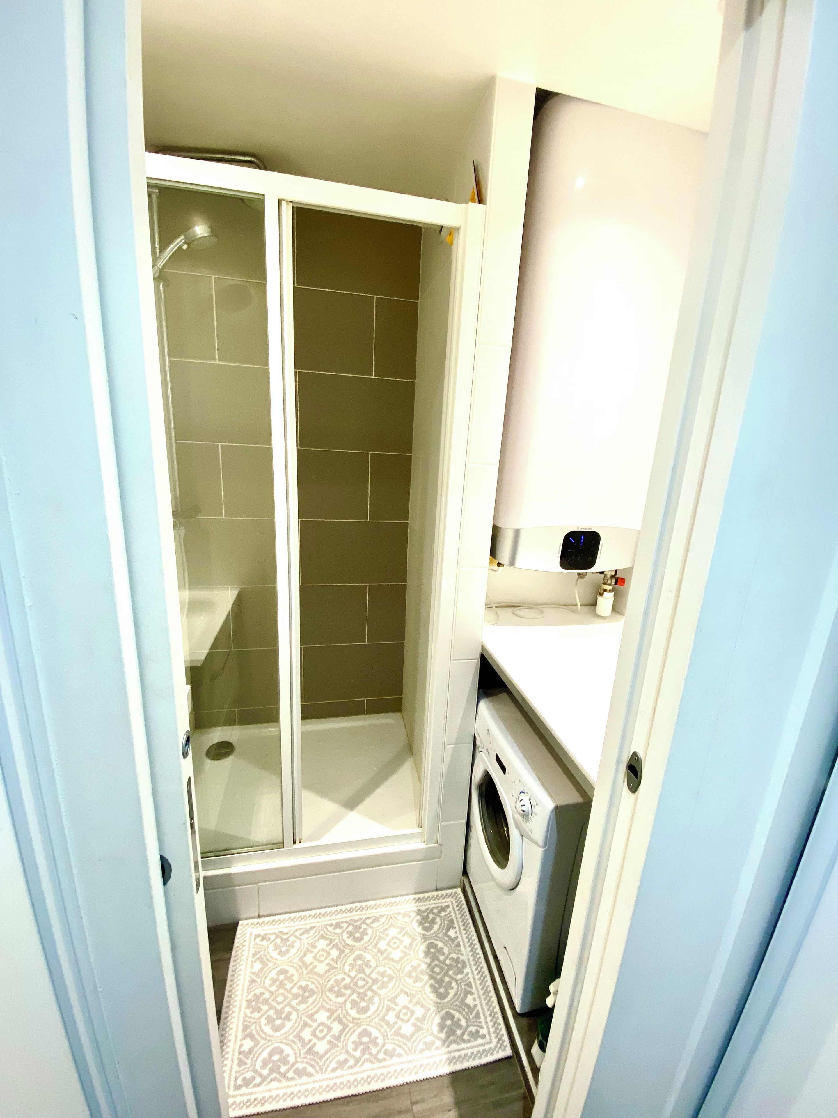 Une petite salle de bain comprenant une douche, des toilettes et un lave-linge.