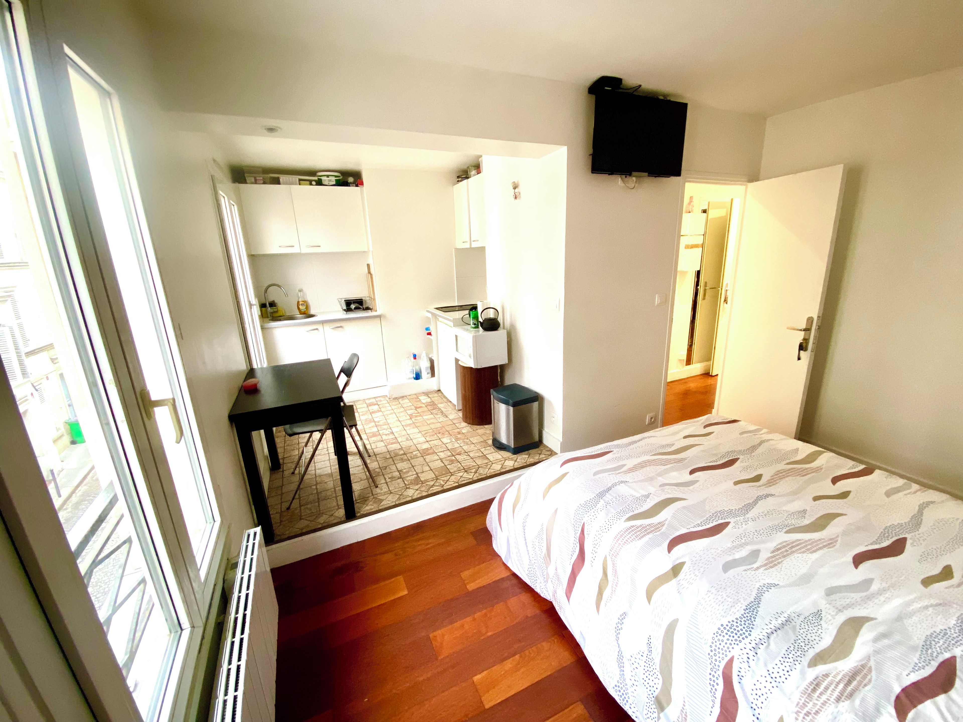 A compact room with a bed, a small table, and a kitchenette area.
