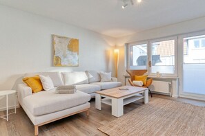 A modern living room with a sofa, coffee table, and a lamp. - Holiday apartment with 1 bedroom (Norderney)