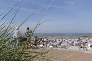 Een strand met gestreepte ligbedden en een fiets.