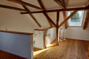 A room with exposed wooden beams, a white radiator, and a window with a view of greenery. - Holiday home in Dunum with sauna (Dunum)