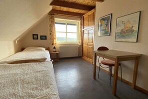 A small, cozy room with two beds, a wooden desk, and a window. - Holiday home with 3 bedrooms (Carolinensiel)