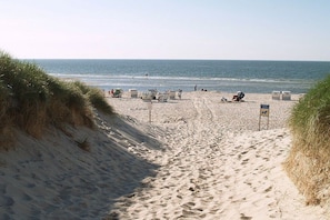A sandy beach path leading to the sea with beach chairs and a sign. - Holiday home with 2 bedrooms (Nebel auf Amrum)