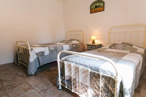 Ein Zimmer mit zwei Betten aus Metall, einem kleinen Nachttisch mit Lampe und einem an der Wand befestigten Schild.