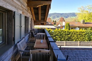 A wooden deck with outdoor seating and a view of a village. - Floor cutting suites summit view (Rottach-Egern)