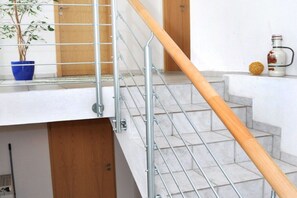 A staircase with a metal railing and wooden handrail, leading to a landing with a potted plant and a bottle. - Holiday apartment in Achslach with Wi-Fi (Achslach)
