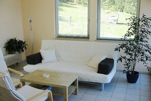 A room with a white sofa, a small table, and a potted plant. - Holiday apartment in Achslach with Wi-Fi (Achslach)
