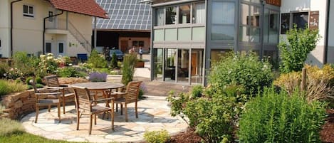 A modern house with a patio, outdoor seating, and a garden.