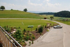 A rural landscape with a paved road, a car, and a fenced area with a bench and picnic table. - Holiday apartment with 1 bedroom (Tettnang)