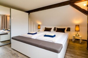 A modern bedroom with a large bed, bedside lamps, and a bench. - Small and charming terraced house (Kühlungsborn)