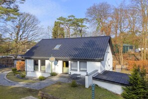 A single-story house with a sloped roof, a visible satellite dish, and a paved driveway. - Holiday apartment with 1 bedroom (Seebad Ahlbeck)