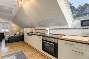 A modern kitchen with a built-in oven, a coffee maker, and a window overlooking a forest. - Holiday apartment with 1 bedroom (Seebad Ahlbeck)