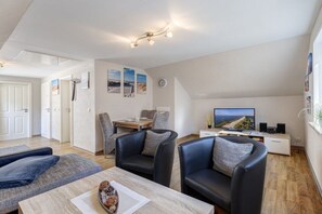 A modern living room with a television, seating area, and a dining space. - Holiday apartment with 1 bedroom (Seebad Ahlbeck)