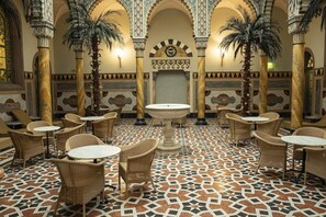 A courtyard with a fountain, palm trees, and patterned flooring. - Moknis Palais Hotel and Spa (Bad Wildbad)