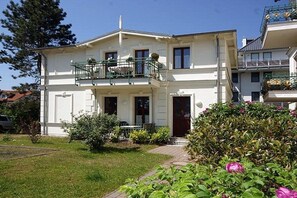 A two-story residential building with a balcony, a front door, and a small garden area. - Holiday apartment with 2 bedrooms (Seebad Heringsdorf)