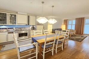 A modern kitchen with white cabinets, a dining table with chairs, and pendant lights. - Holiday apartment with 2 bedrooms (Seebad Heringsdorf)