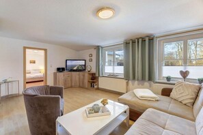 A modern living room with a sofa, armchair, coffee table, and a television. - Villa "Helma" Apartment 1 (Seebad Heringsdorf)